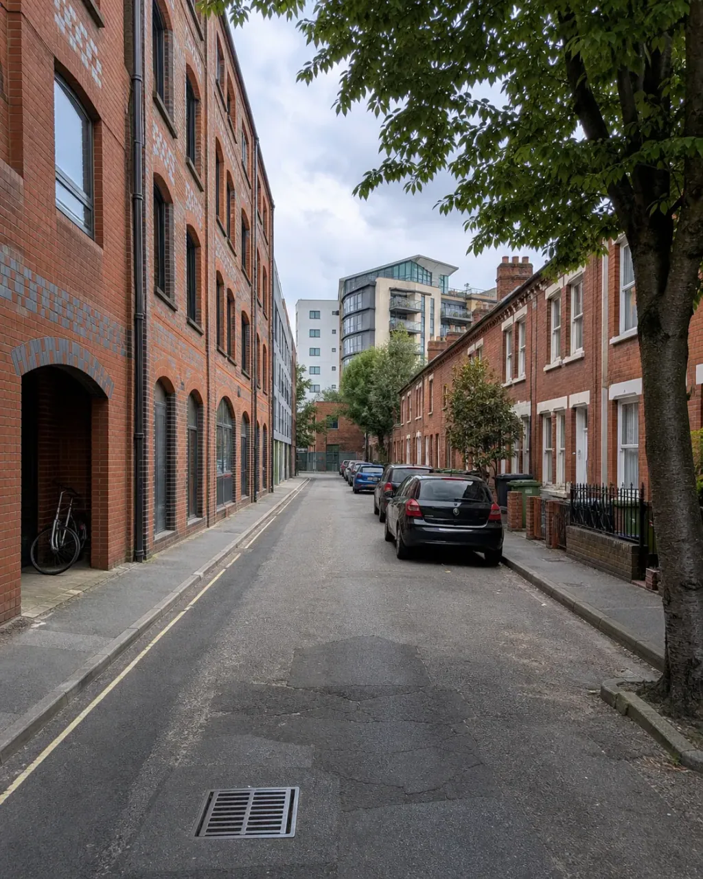 A quiet side street off Reading town centre, converted red-brick warehouse flats facing a short Victorian terrace, taller modern blocks closing the view