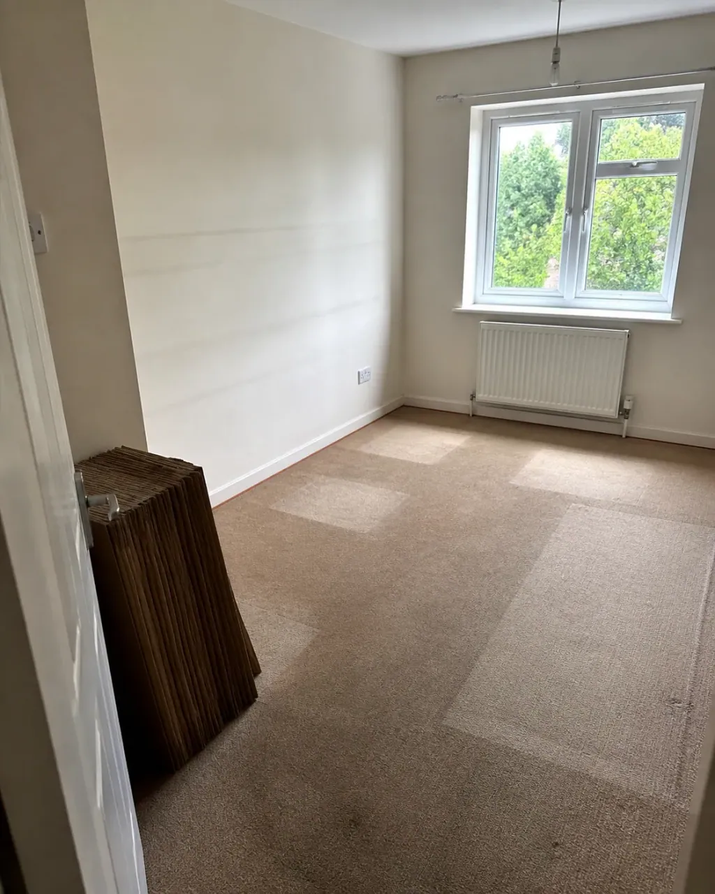 A newly emptied room, pale marks on the carpet where stacks stood and flattened boxes ready by the door